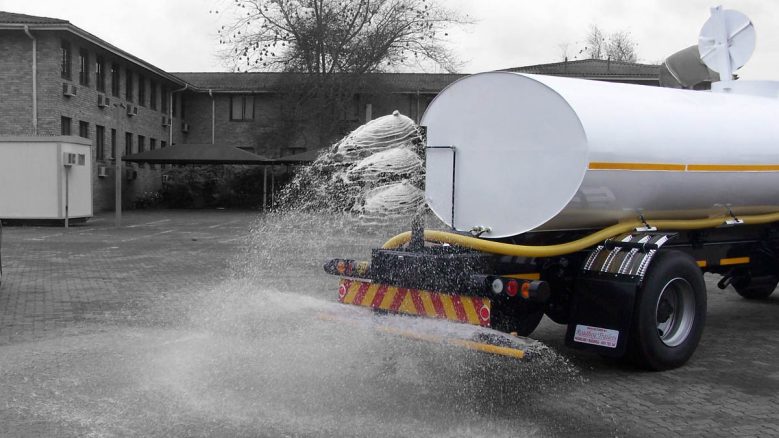 16000 litre rigid water tanker with rear sprayers distributing water on payving